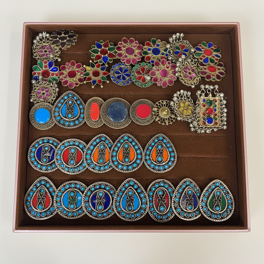 Assorted colorful Afghani rings displayed in a studio jewelry tray